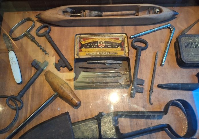 vintage shadow box containing a mix of antique tools, keys, and a loom.