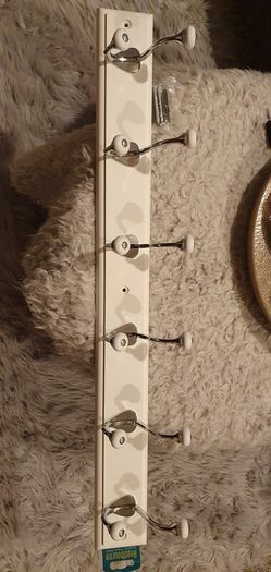 Coat and hats chrome hooks on white board.