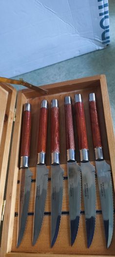A Newbridge Cuisine set of six steak knives with serrated blades and wooden handles.
