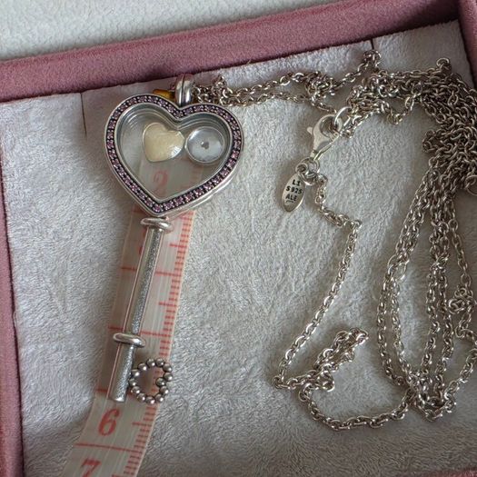 Pandora sterling silver key necklace with a heart,shaped floating locket and pink sparkling stones. Includes the two petite charms