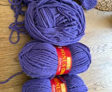 2.5 balls of purple wool and set of knitting needles