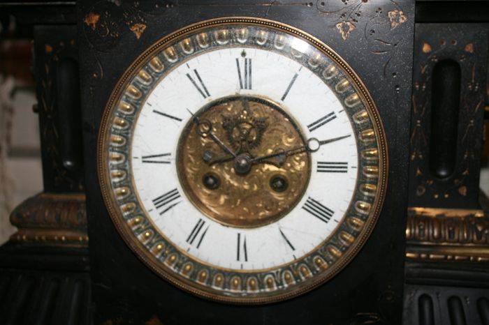 Victorian French Black Slate Mantle Clock (Very large and heavy) with bronze ornamentation Oversized. Open escarpment slate plate Roman numerals. Circa 1890s. Accented with Trojan head. Flanked by two Hellenistic ladies heads on sides. Rose cartouche mask