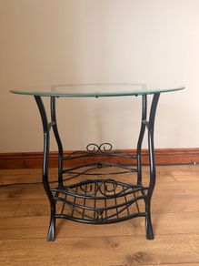 Black metal-framed glass console table with ornate scrollwork