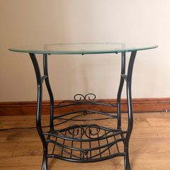 Black metal-framed glass console table with ornate scrollwork