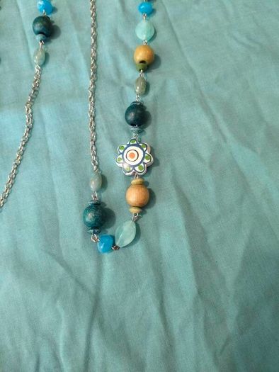long, colorful beaded necklace featuring a mix of wood, blue, and white floral beads.