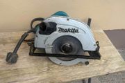 Makita 110V corded circular saw, likely a large 235 mm model, with dust-extraction port