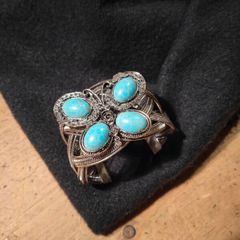 silver tone butterfly cuff bracelet featuring faux turquoise stones and intricate wire work.