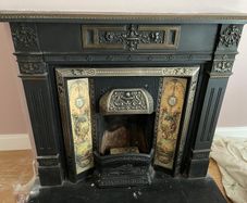Late Victorian / early Edwardian style cast iron fireplace with tiled inserts and a decorative mantel surround
