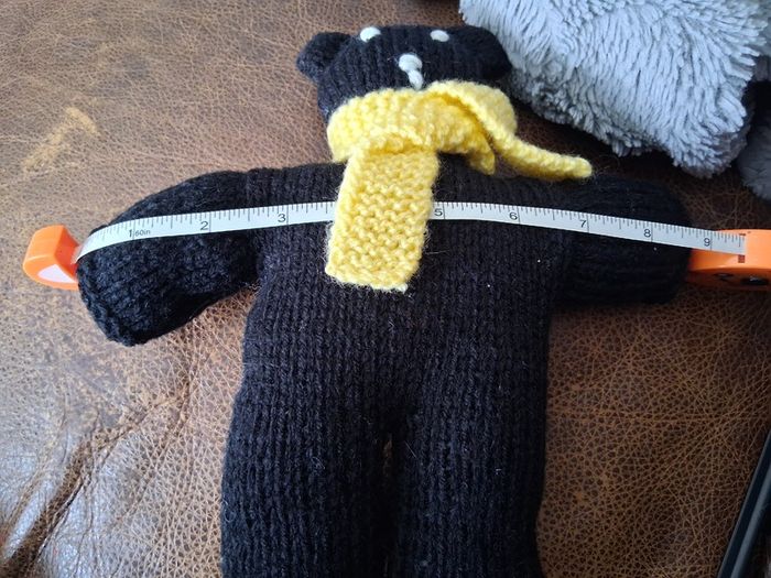 Hand knitted black teddy bear with yellow scarf