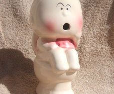 A vintage novelty money box in form of a young child sitting on a toilet (1930s to 1960s)