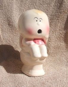 A vintage novelty money box in form of a young child sitting on a toilet (1930s to 1960s)