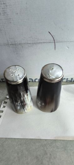 Set of 2 Buffalo Horn  Salt And Pepper Set topped with mother of pearl rimmed with sterling silver rim stamped.