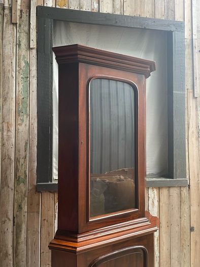 A tall mahogany corner cabinet.