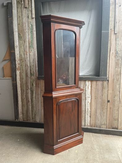 A tall mahogany corner cabinet.