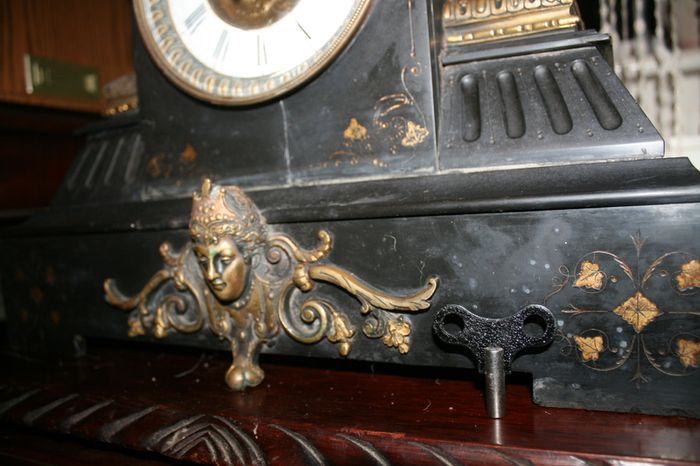 Victorian French Black Slate Mantle Clock (Very large and heavy) with bronze ornamentation Oversized. Open escarpment slate plate Roman numerals. Circa 1890s. Accented with Trojan head. Flanked by two Hellenistic ladies heads on sides. Rose cartouche mask