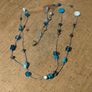 long necklace featuring a mix of blue-toned glass beads and silver-colored accent beads on a thin gray cord Image 3