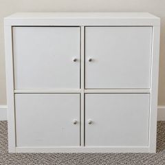 IKEA KALLAX 2x2 storage unit in white, fitted with 4 individual cupboard door inserts.