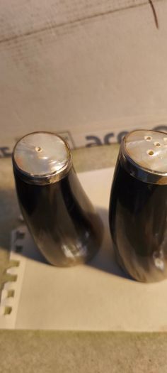 Set of 2 Buffalo Horn  Salt And Pepper Set topped with mother of pearl rimmed with sterling silver rim stamped.