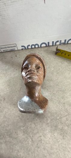 vintage image shows a handcrafted stone bust of a woman wearing a headscarf, often associated with Shona sculpture be carved from fruit serpentine stone from Zimbabwe