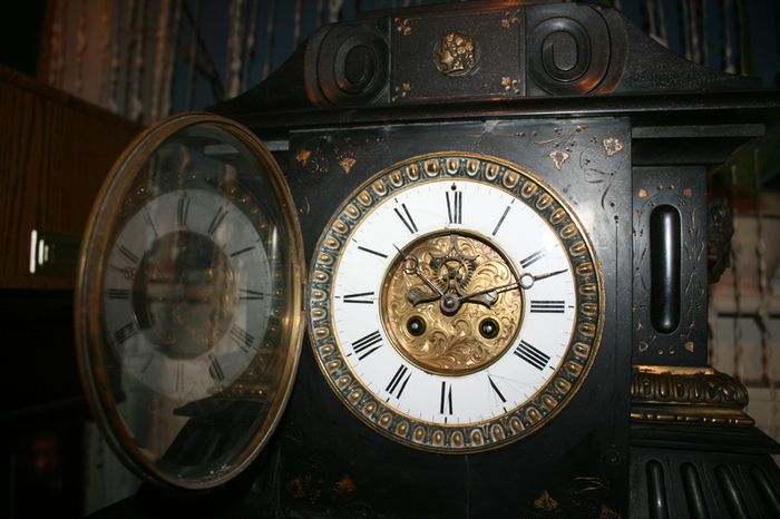 Victorian French Black Slate Mantle Clock (Very large and heavy) with bronze ornamentation Oversized. Open escarpment slate plate Roman numerals. Circa 1890s. Accented with Trojan head. Flanked by two Hellenistic ladies heads on sides. Rose cartouche mask