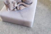 Small cat on marble plinth.