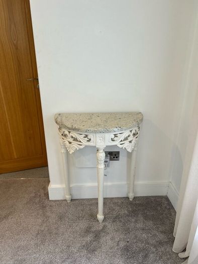 ornate half-moon console table with a granite top