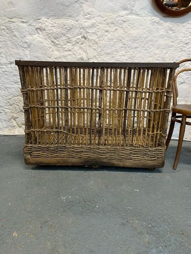 Large Victorian cane and metal laundry basket on wheels.