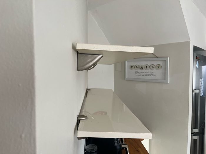 A pair of e floating wall shelves mounted on decorative metal shelf brackets.