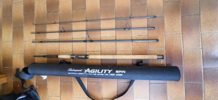 Shakespeare Agility Spin fishing rod. 11 feet (3.30 meters) in length. The item includes a black carrying tube with a strap for transport.