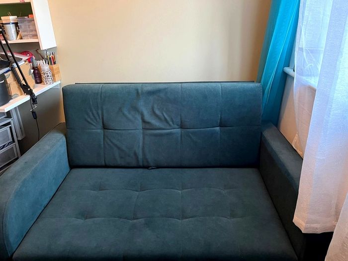 Grey fabric sofa bed with large storage compartment.