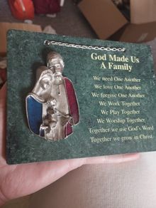 A vintage green marble wall plaque with a metal sculpture of the Holy Family.