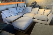 Grey corner sofa with scatter cushions and footstool