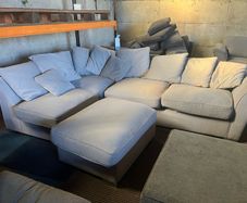 Grey corner sofa with scatter cushions and footstool