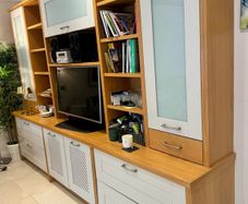 large wooden entertainment center or wall unit featuring a mix of open shelving, glass fronted cabinets, and lower drawers