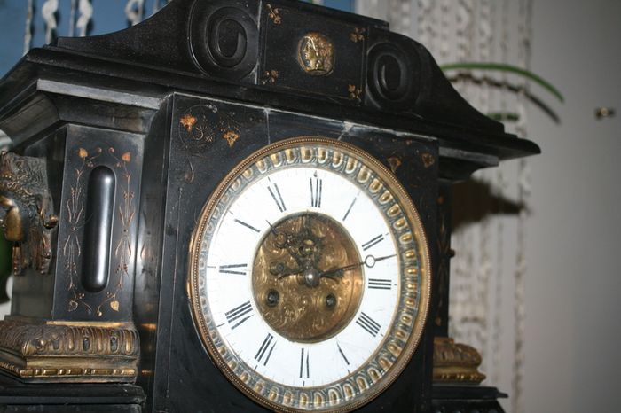 Victorian French Black Slate Mantle Clock (Very large and heavy) with bronze ornamentation Oversized. Open escarpment slate plate Roman numerals. Circa 1890s. Accented with Trojan head. Flanked by two Hellenistic ladies heads on sides. Rose cartouche mask