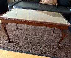 Vintage Queen Anne-style wooden coffee table featuring cabriole legs, a glass top protecting an inset leather surface with gold tooling