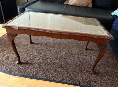 Vintage Queen Anne-style wooden coffee table featuring cabriole legs, a glass top protecting an inset leather surface with gold tooling
