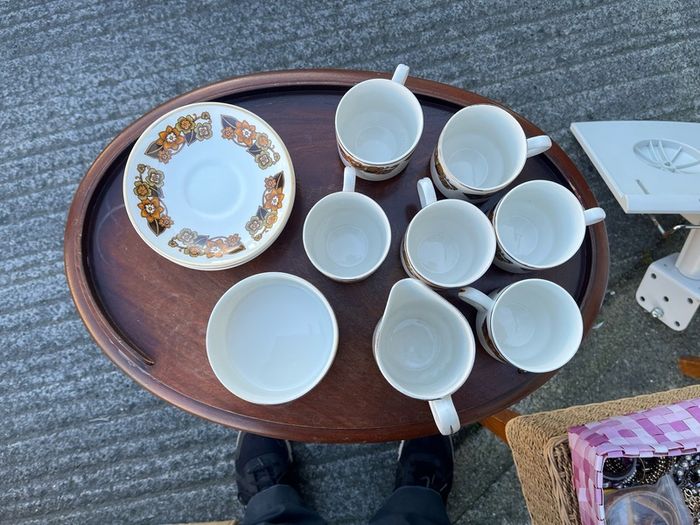 The set shown is a 1970s Arklow Pottery "Studio Kraft" tea/coffee set manufactured in County Wicklow, Ireland. It features a classic 1970s mid-century retro floral pattern in amber, orange, and brown tones with gold trim