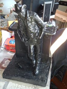 Large Cowboy Sculpture is titled Cutting the Dust and was created by artist Michael Garman. It is a Western Themed piece featuring a Cowboy Leaning Against a Counter,