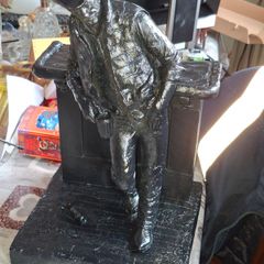 Large Cowboy Sculpture is titled Cutting the Dust and was created by artist Michael Garman. It is a Western Themed piece featuring a Cowboy Leaning Against a Counter,