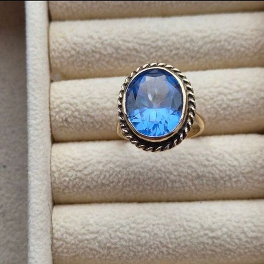 Beautiful 9K gold ring featuring a stunning large oval blue stone.