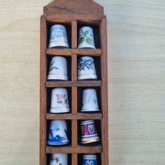 Collectible porcelain thimbles in a wall-mounted wooden display case
