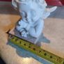 A small clay figure of an white angel on a marble plaint . Image 2