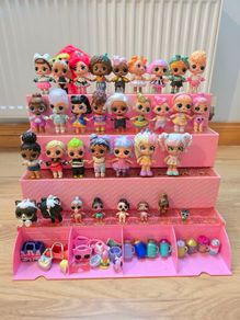 A lot of L.O.L. Surprise dolls with accessories and a doll podium.