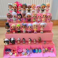 A lot of L.O.L. Surprise dolls with accessories and a doll podium.