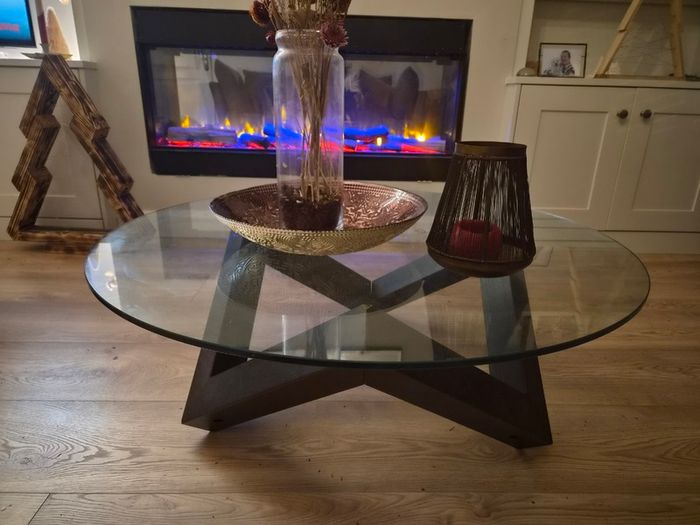 Round glass coffee table with dark wood base