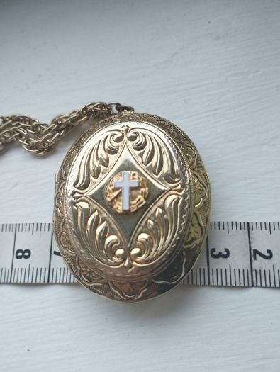 A large medallion featuring religious symbols, suspended from a long chain.
