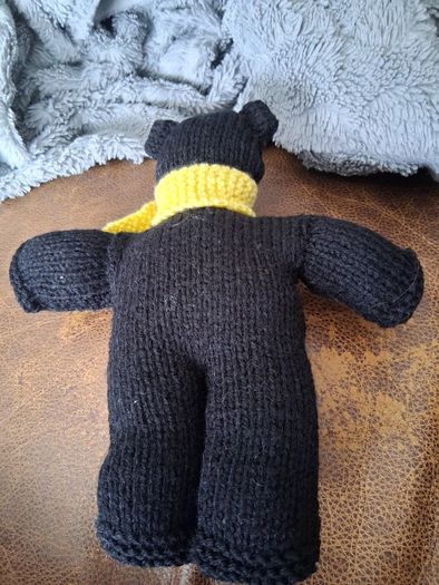 Hand knitted black teddy bear with yellow scarf