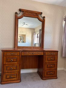 Crafted from stained hardwood with raised drawer panels, rounded pedestal edges, and an arched top mirror crown bordered by heavy metal or wood accent brackets. Nautical Rope Detailing: The upper accent panels on the mirror frame, the top left drawer, and