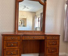 Crafted from stained hardwood with raised drawer panels, rounded pedestal edges, and an arched top mirror crown bordered by heavy metal or wood accent brackets. Nautical Rope Detailing: The upper accent panels on the mirror frame, the top left drawer, and